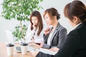 オフィスでデザインに頭を悩ませる複数社員