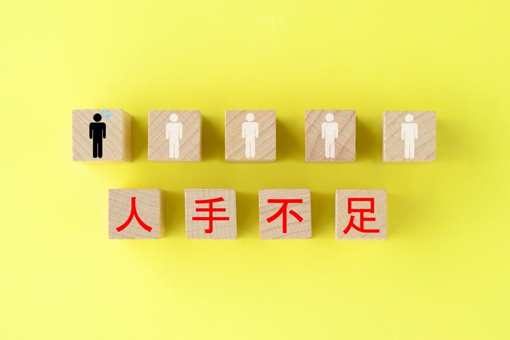 上下に並んだ人形のイラストが書かれた5つのキューブと「人手不足」と一文字ずつ書かれた4つのキューブ