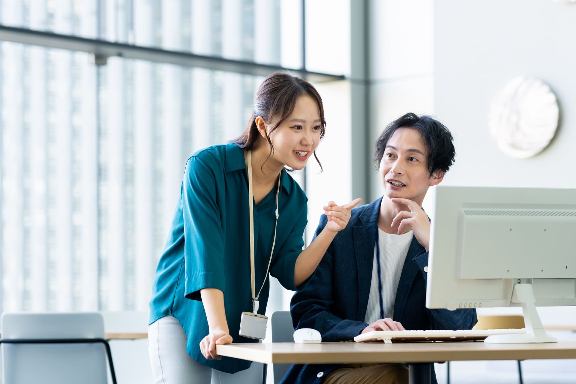 オフィスでPCを前にデザインの打ち合わせをする男女