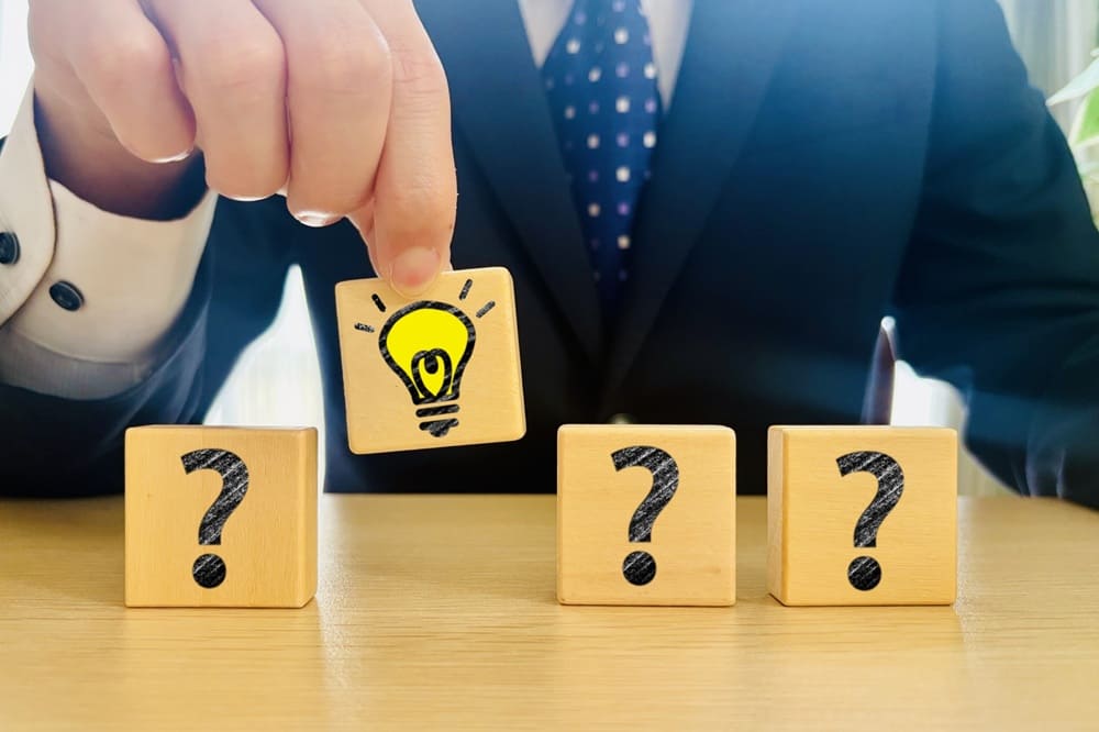 電球が輝いてひらめきを表現した積み木をつまみ上げているスーツの男性