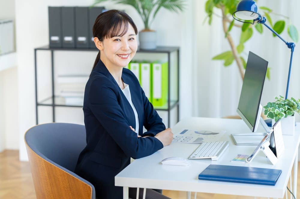 オフィスでノートパソコンを開いてるオフィスカジュアルの女性