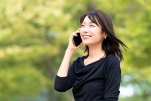 外でスマホで会話している笑顔の女性