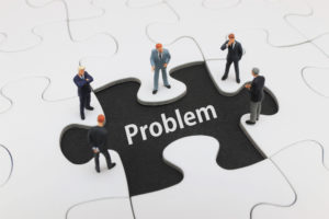 パズルのピースの上に立つビジネスマンたち。「Problem」と書かれたピース。