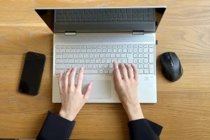 ノートPCに文字を打ち込んでいる両手