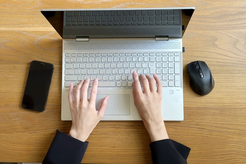 ノートPCに文字を打ち込んでいる両手