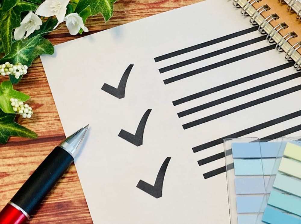 チェック項目とそれを囲むように置かれたボールペンと付箋、ノート