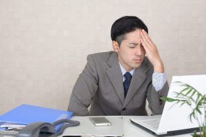 おでこに手を当てて悩んでいる男性ビジネスマン