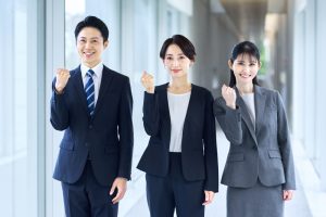 ガッツポーズをしているスーツの男女3人