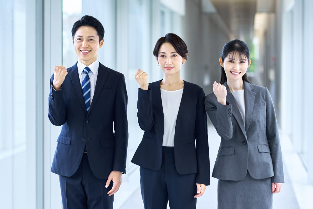 ガッツポーズをしているスーツの男女3人