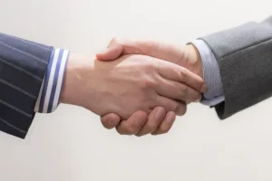 外部の営業支援パートナーと固い握手を交わすビジネスパーソン