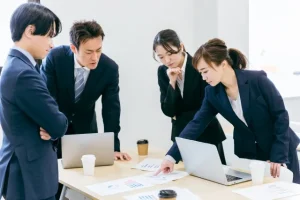 パソコンと資料を見ながら打ち合わせをする、Web制作会社の営業とディレクター