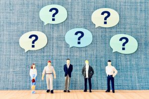 デザイン依頼に関するよくある質問や疑問を抱える、企業担当者たちのミニチュア