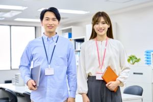専門派遣会社が提案する優秀な人材:オフィスでファイルとタブレットを持つ男女のビジネスパーソン