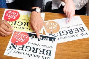 社会人男女がデザインが異なる広告をそれぞれ指さしている