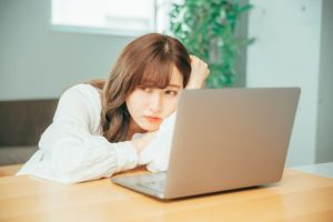 ノートPCの前で退屈そう突っ伏しているビジネスウーマン