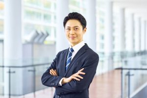 腕組みをして微笑んでいるスーツの男性会社員