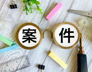 「案件」という文字が書かれたおもちゃの眼鏡とそれを囲むように置かれた複数の文具
