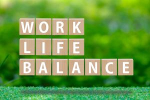 ぼやけた木々を背景にWORK LIFE BALANCEと一文字ずつ書かれた立方体が並んでいる