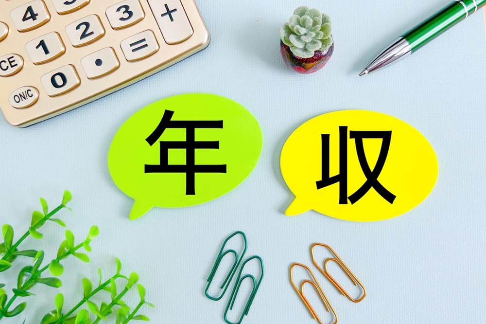「年収」の文字を取り囲む電卓、クリップ、ペン