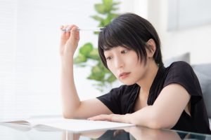 ペンで頭をかきながらポートフォリオのアイデアを考えているショートヘアの女性