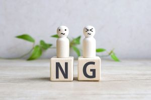 「NG」と書かれた木製のブロックとそのうえに乗っている2体の人形