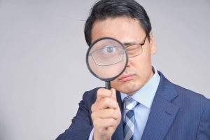 虫眼鏡からのぞいているスーツの男性