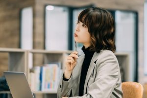 PCを開いて考える女性