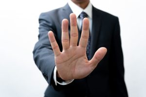 手のひらをこちらに向けて止める男性