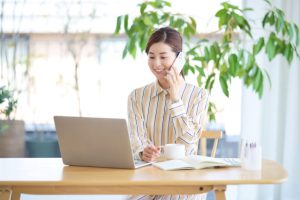 柔軟な時短勤務を活用し、パソコンを開きながら笑顔で電話対応をする女性